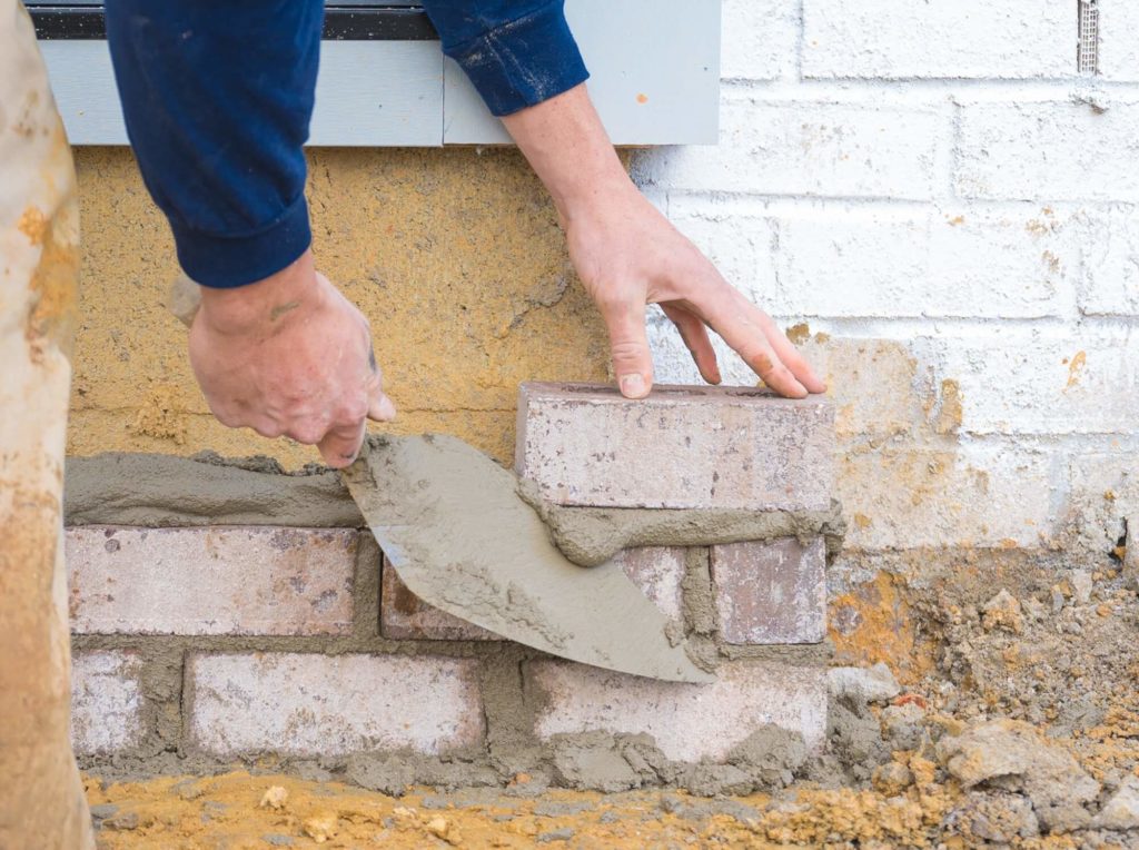 Bricklayer setting brick on an exterior wall