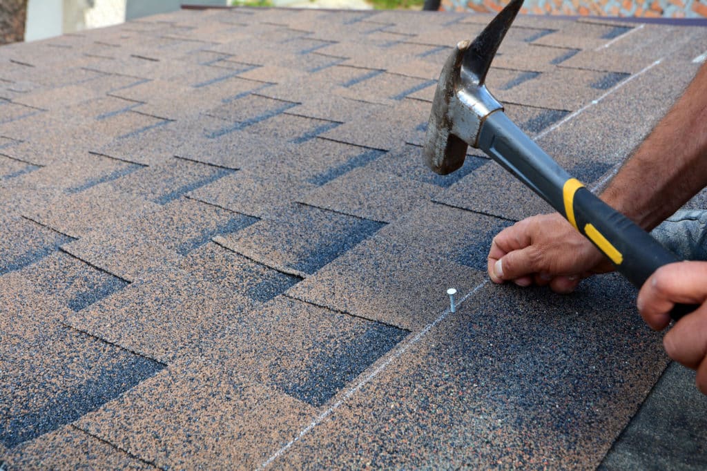 Installing asphalt roof shingles with a hammer