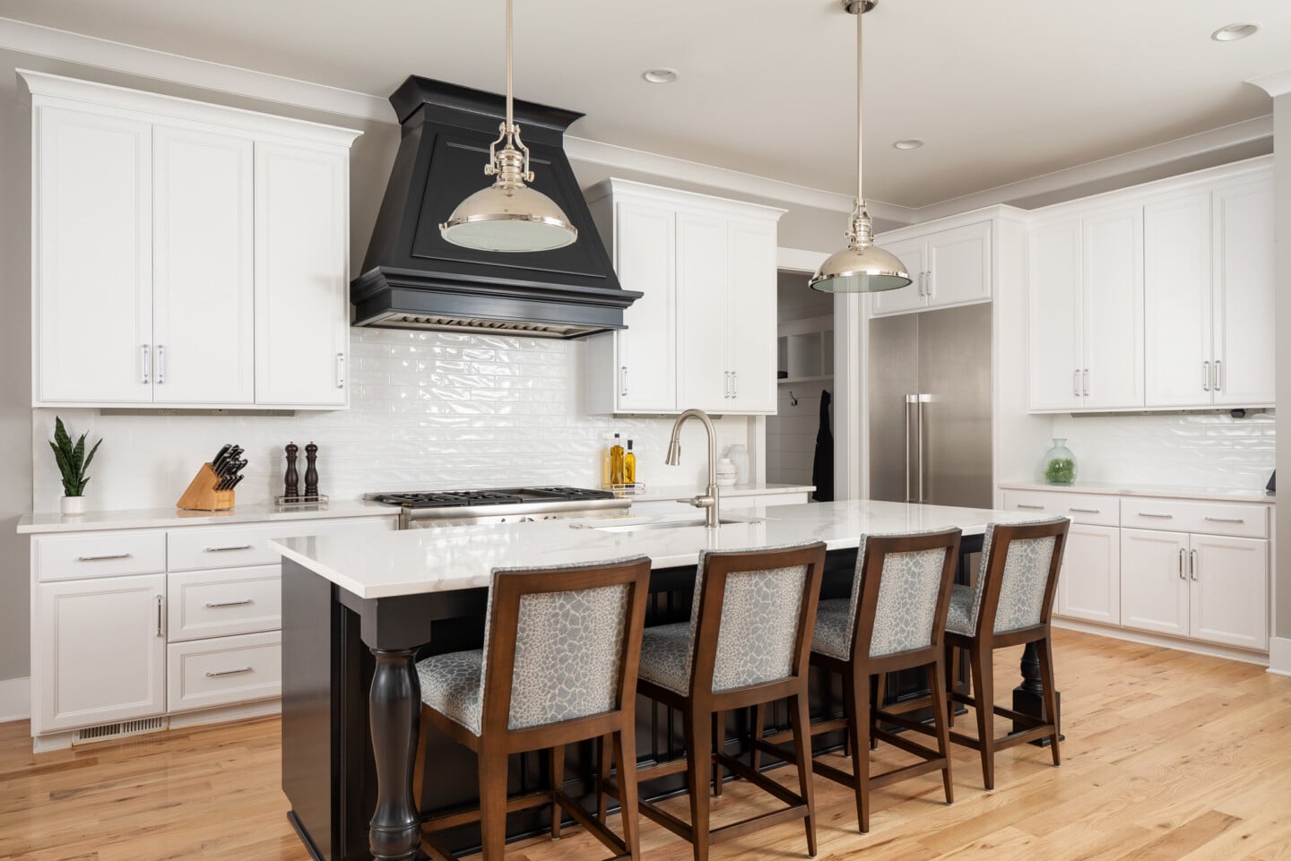 White kitchen with black hood and island with bar seating