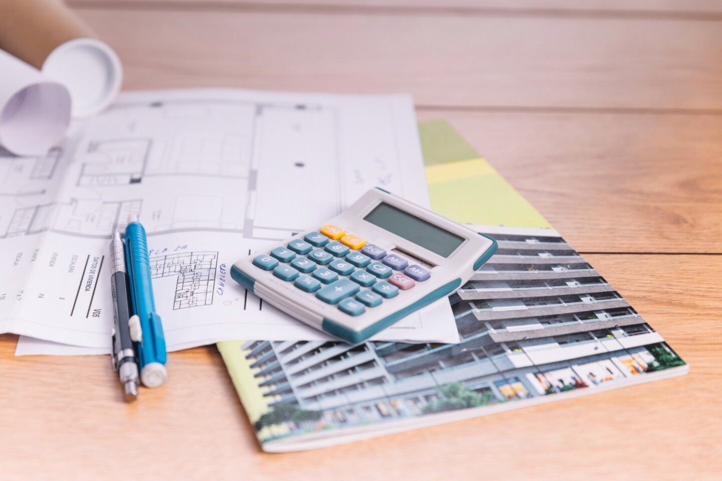 Calculator, pen and house blueprints used to estimate the cost to build a house in North Carolina