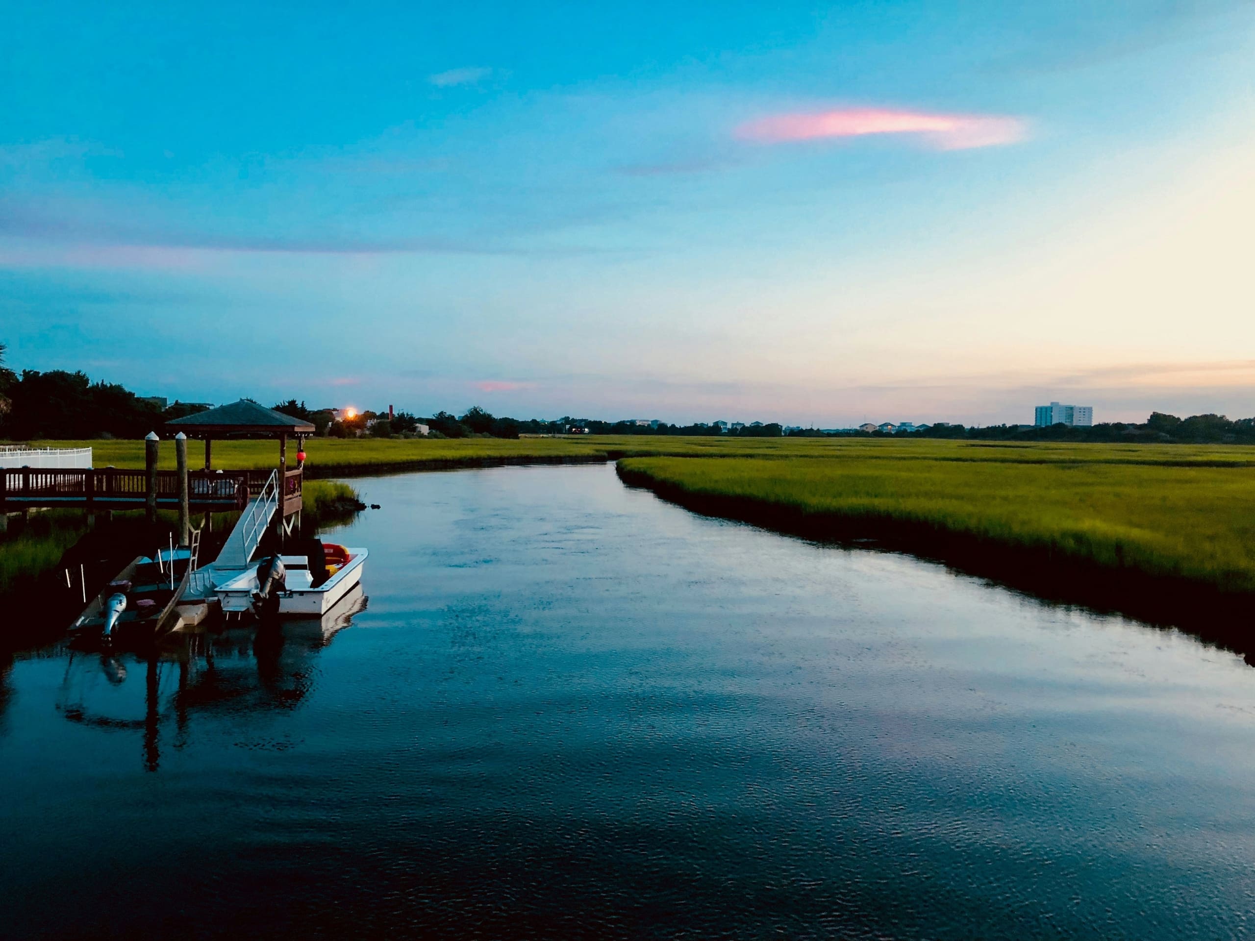 Waterfront land at sunset with a dock, the kind of site considered when building a home on your own land