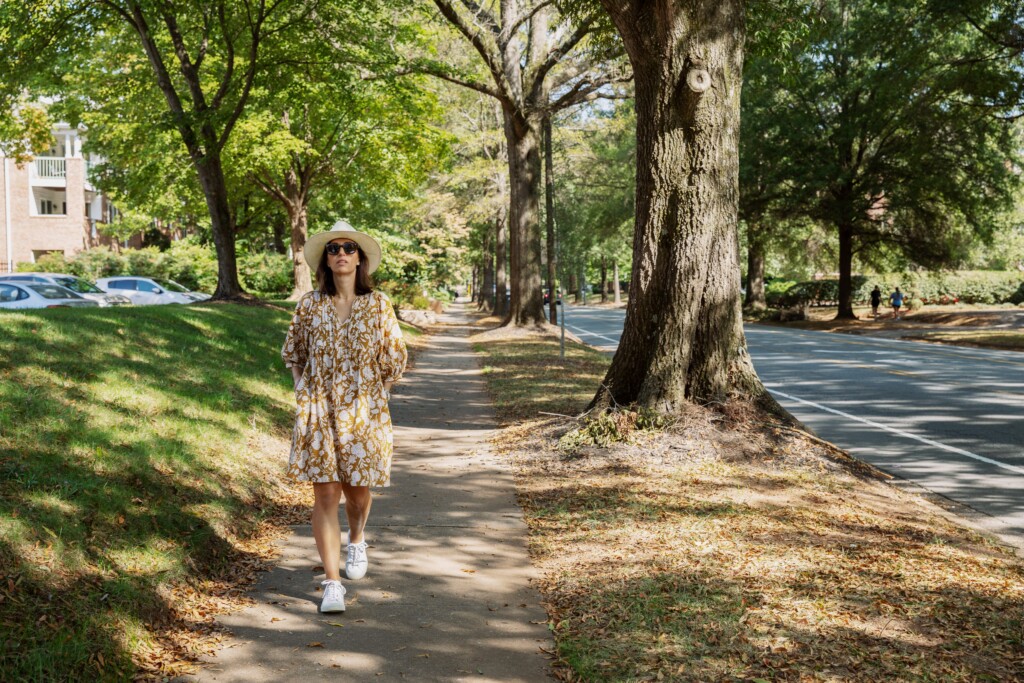 Woman walking along a tree-lined sidewalk in a Charlotte neighborhood
