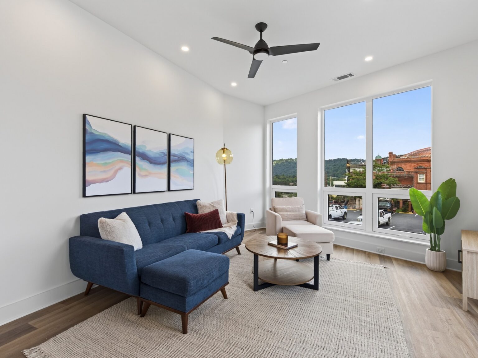 Living room in condo 404 with blue sectional and large windows facing downtown Asheville