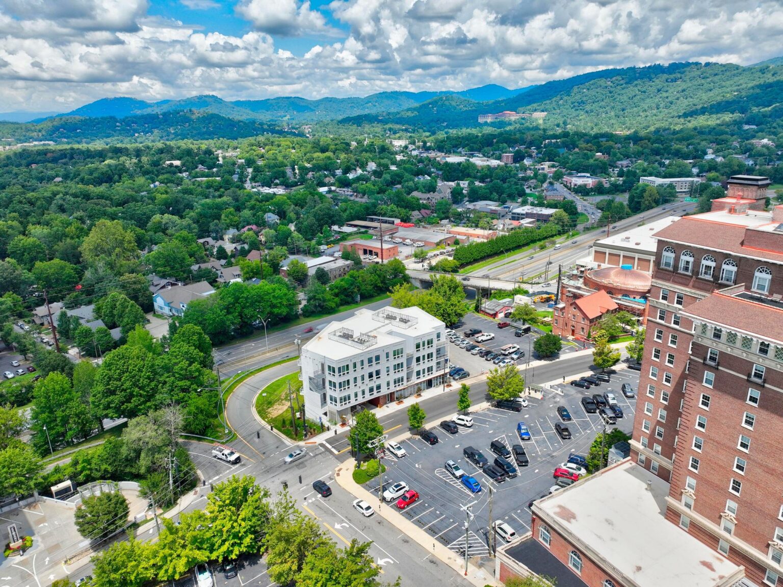 Aerial view of One23 Haywood condos in downtown Asheville with the Blue Ridge Mountains behind