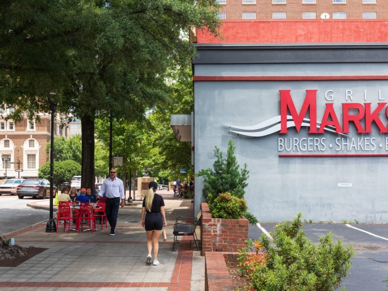 Greenville, SC, USA-23 June 2021: Mark's Grill, on Main St., showing diners at sidewalk table, passersby on sidewalk.